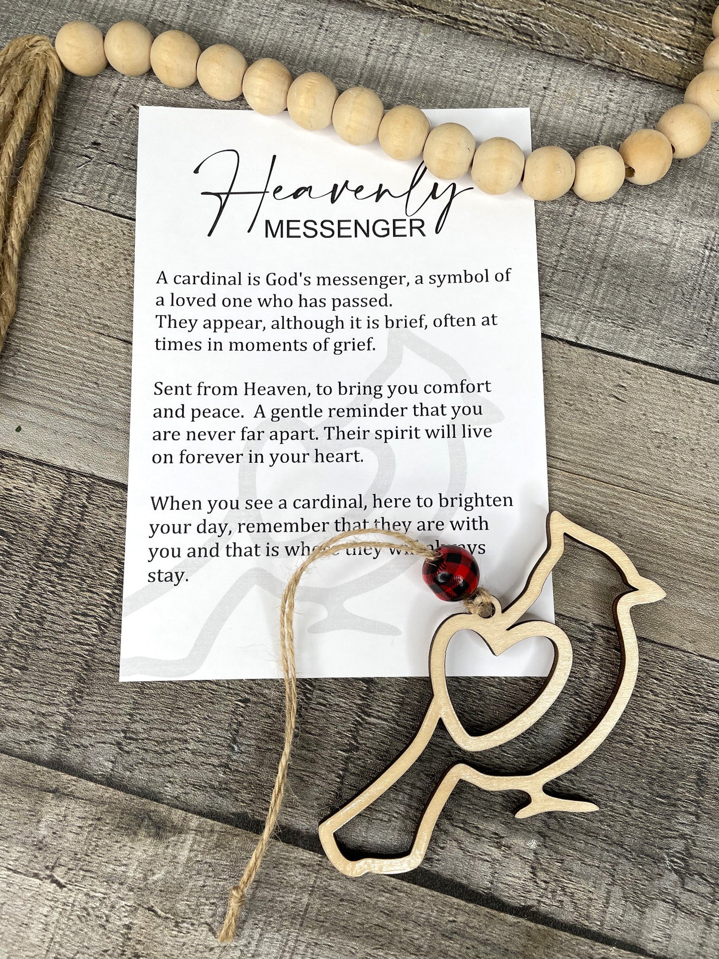 A handcrafted story charm featuring a wooden bird-shaped figure attached to a card with an inspirational message, placed on a wooden surface.