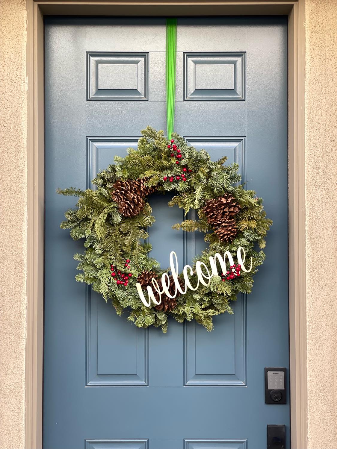 Welcome sign on christmas wreath hanging on front door of the house