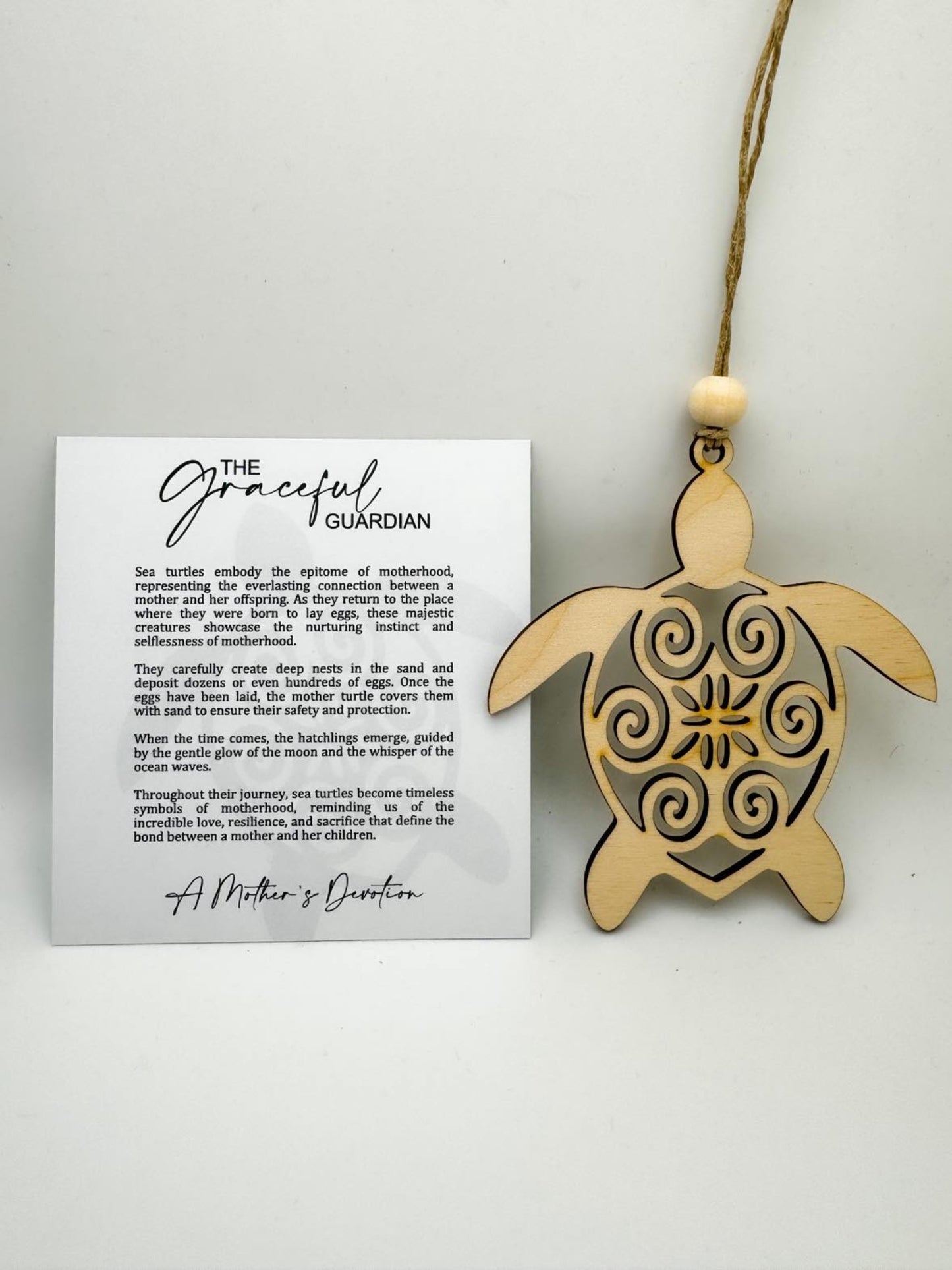 A wooden sea turtle-shaped charm with a card attached that has text, likely a story or quote, and a natural wood bead is not shown.