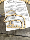 A gold-colored bear-shaped charm with a story card attached, placed on a wooden surface.