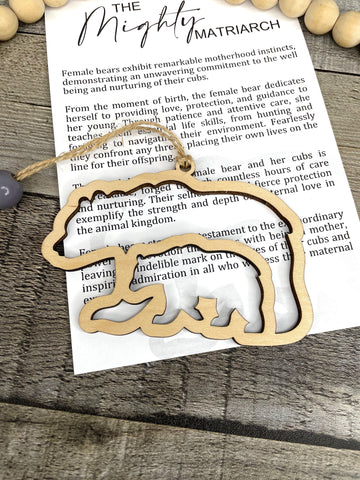 A gold-colored bear-shaped charm with a story card attached, placed on a wooden surface.