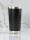 Black tumbler with silver base and rim on a marble background