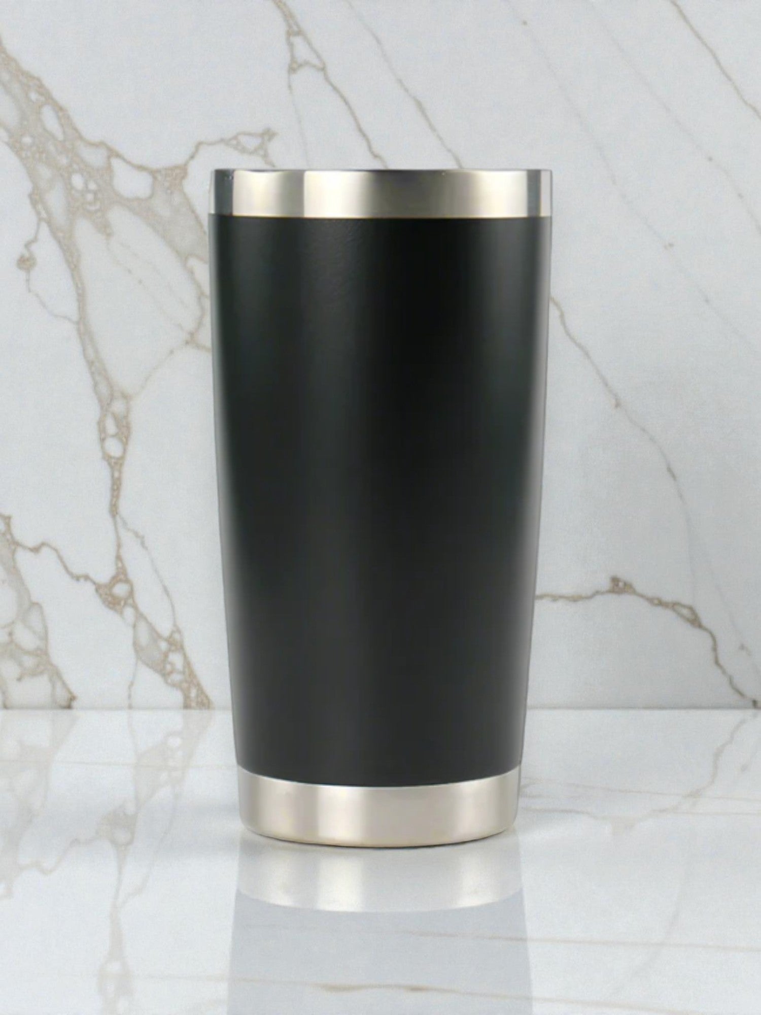 Black tumbler with silver base and rim on a marble background