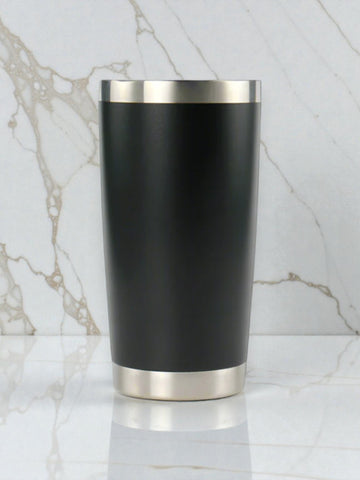 Black tumbler with silver base and rim on a marble background