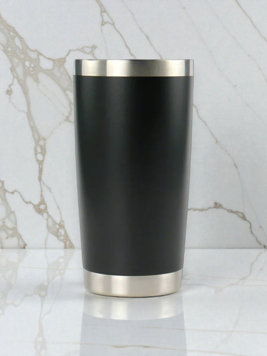 Black tumbler with silver base and rim on a marble background