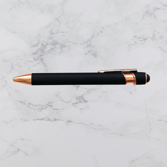 Black pen with rose gold accents on a marble surface