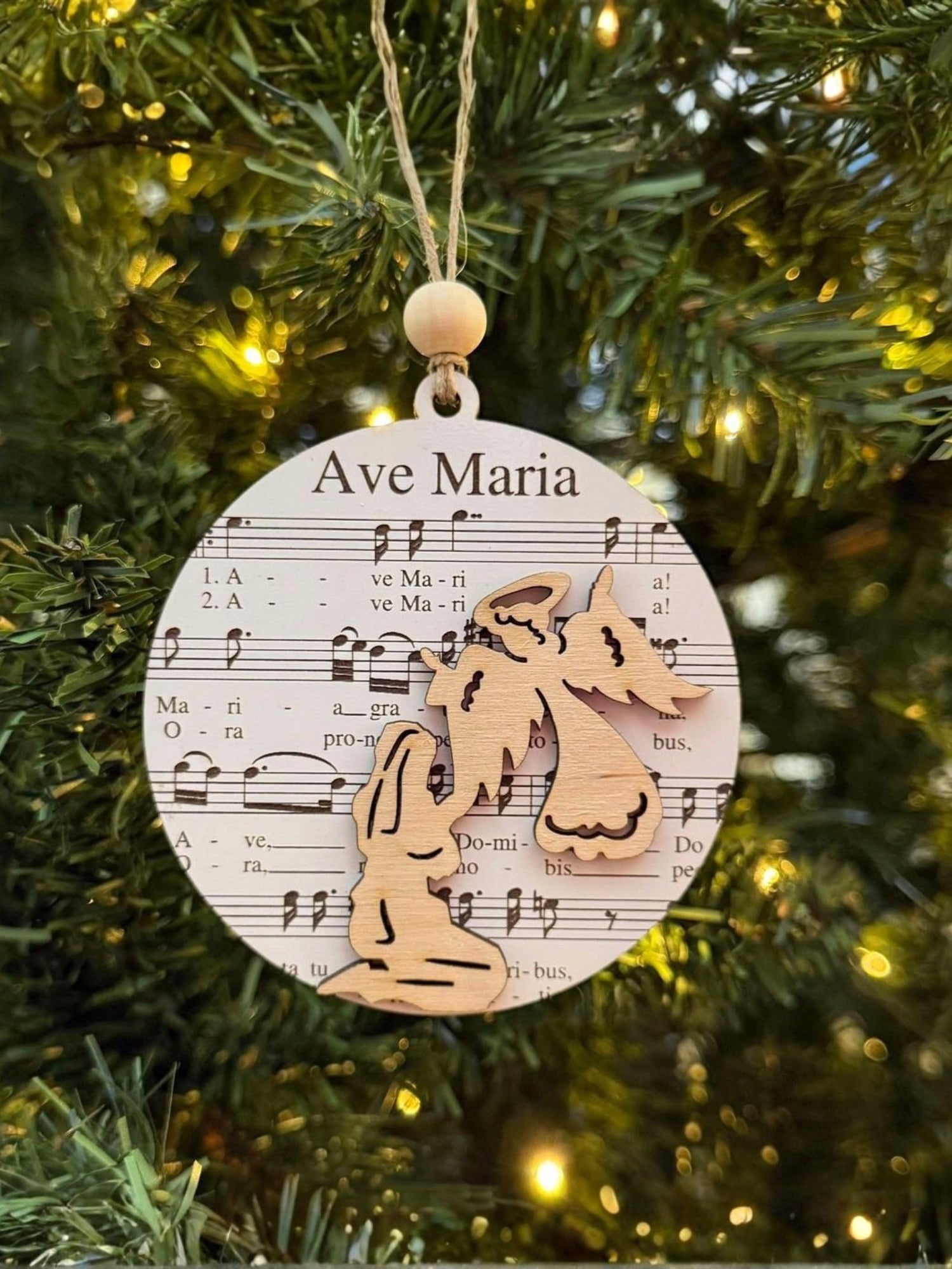Decorative Christmas ornament with 'Ave Maria' text and music notes on a tree.