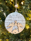 Decorative Christmas ornament with sheet music and angel design on a tree.