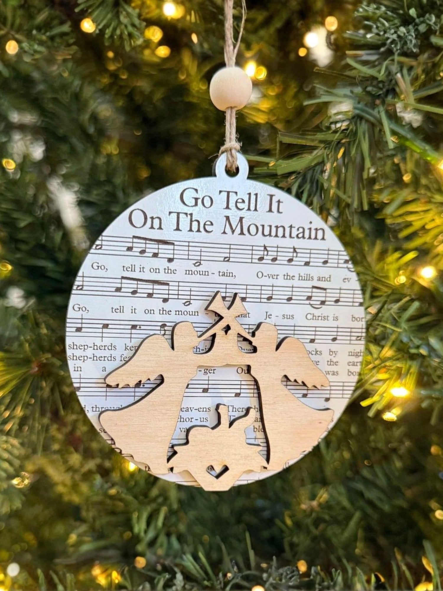 Decorative Christmas ornament with sheet music and angel design on a tree.