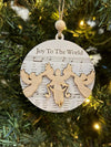 Decorative Christmas ornament with 'Joy To The World' text and angel design on a tree.