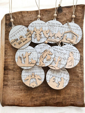 Set of Christmas ornaments with nativity scenes and lyrics on a wooden surface