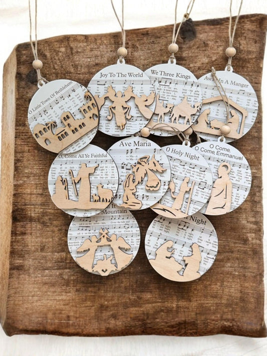 Set of Christmas ornaments with nativity scenes and lyrics on a wooden surface