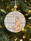 Decorative Christmas ornament with sheet music and a wooden figure of a baby on a Christmas tree.