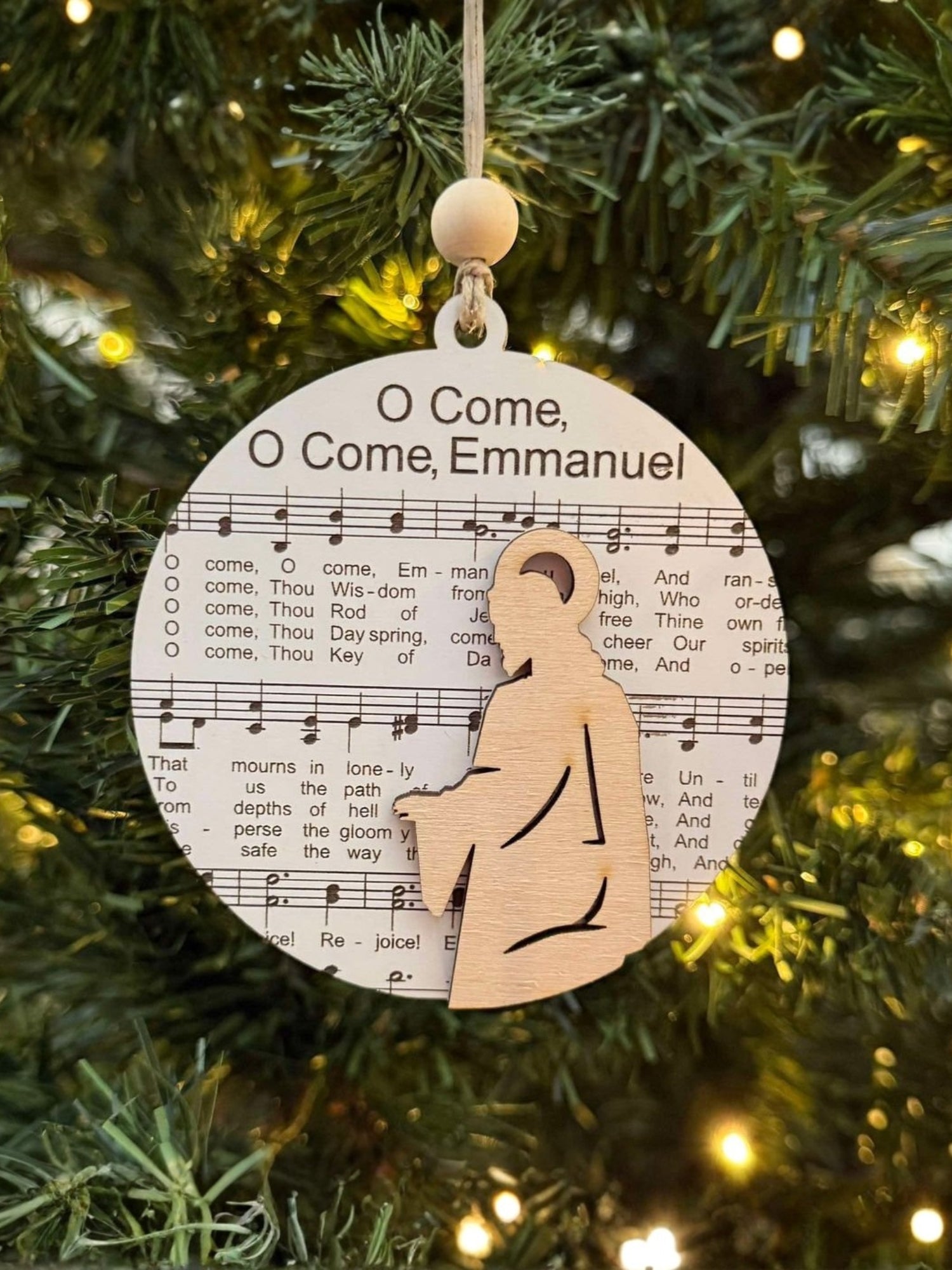 Decorative Christmas ornament with sheet music and a wooden figure of a baby on a Christmas tree.