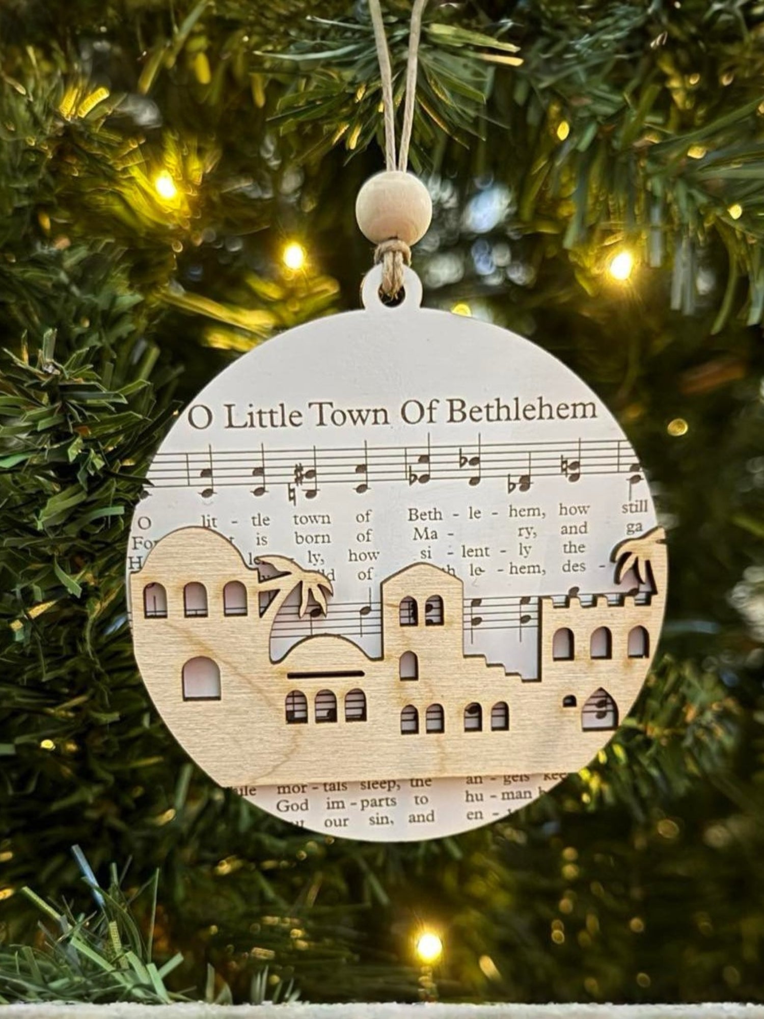 Decorative Christmas ornament with a town design on a tree.