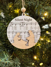 Decorative ornament with 'Silent Night' lyrics on a Christmas tree.