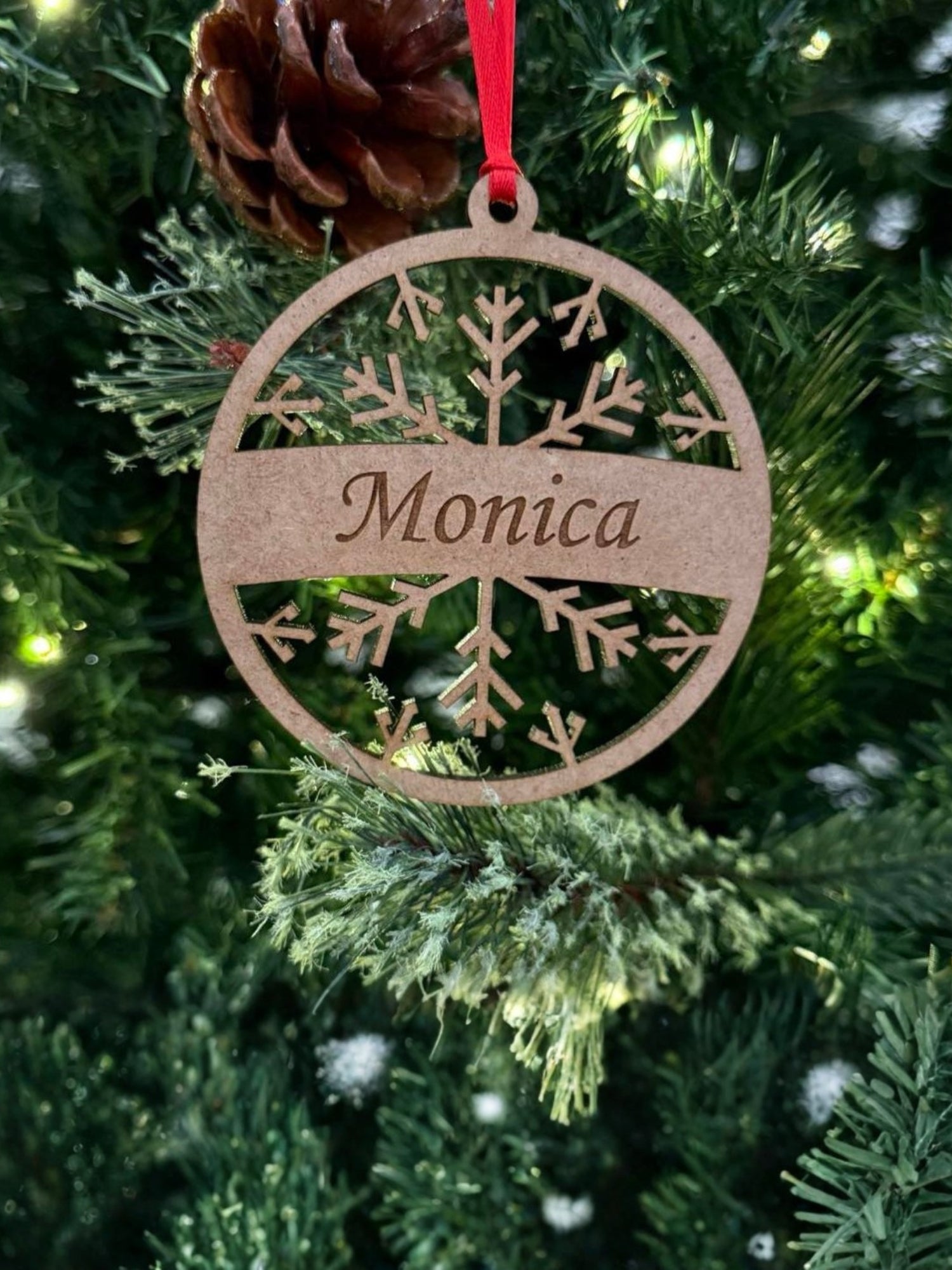 Wooden ornament with 'Monica' engraved on a Christmas tree