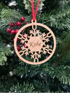 Wooden snowflake ornament with 'Kobe' engraved, hanging on a Christmas tree.
